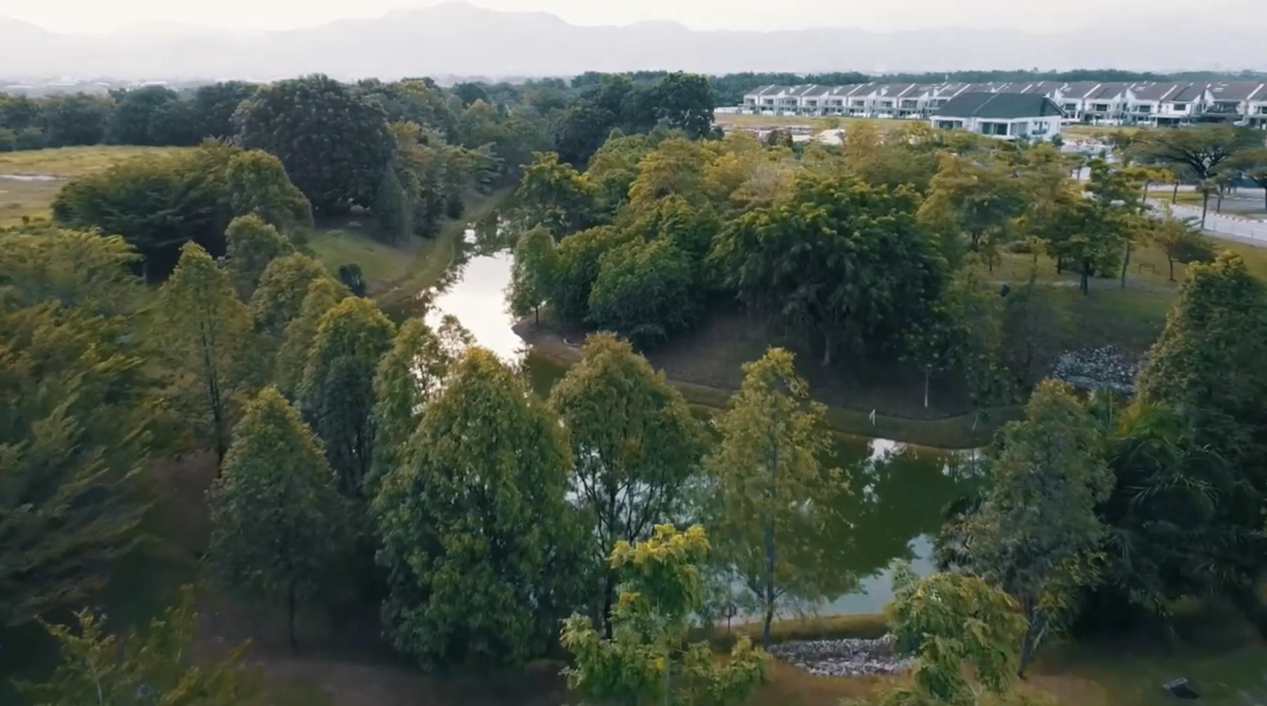 Aerial view of the green open field and lake beside Taman Lapangan Indah, Botani Ipoh